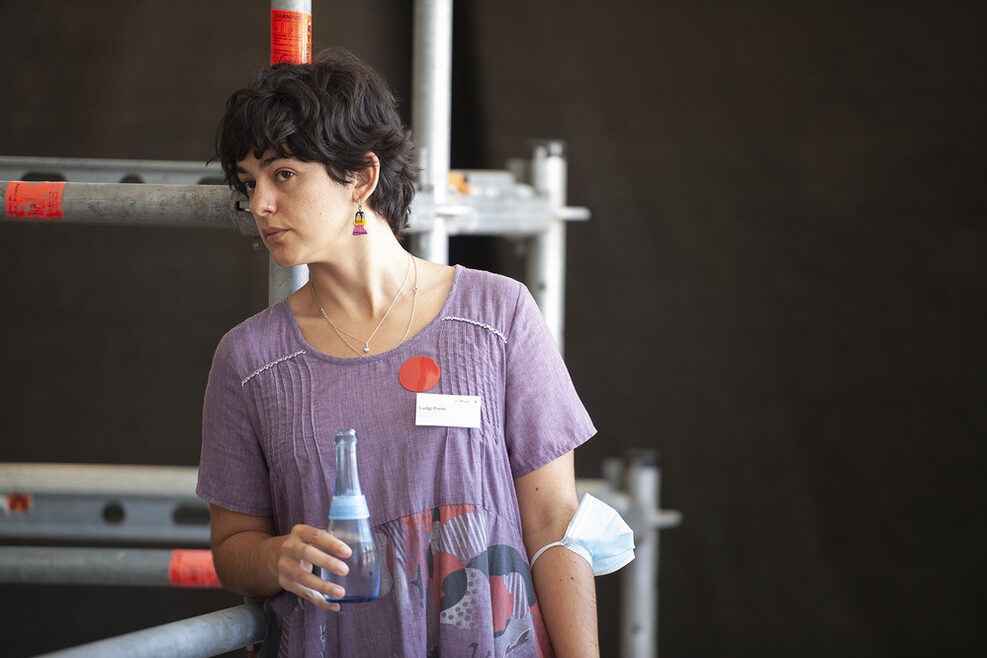 Eine Frau mit Flasche in der Hand schaut interessiert bei der Veranstaltung zu.