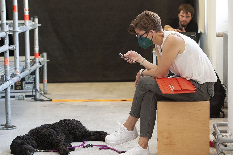 Eine Teilnehmerin schaut in ihr Mobiltelefon, ihr Hund liegt vor ihr.