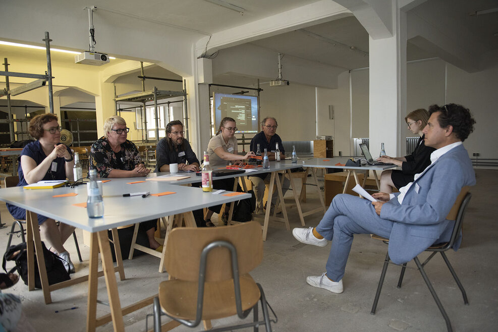 Moderierte Gruppenarbeit ein einem Holztisch in U-Form.