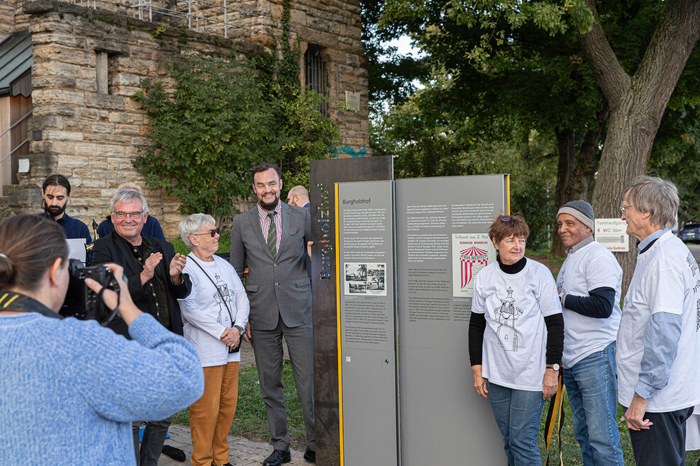 Der Leiter des Kulturamts Marc Gegenfurtner und Mitglieder der Bürgerinitiative Burgholzhof stehen vor der neuen Infostele zur Geschichte des Stadtteils Burgholzhof.