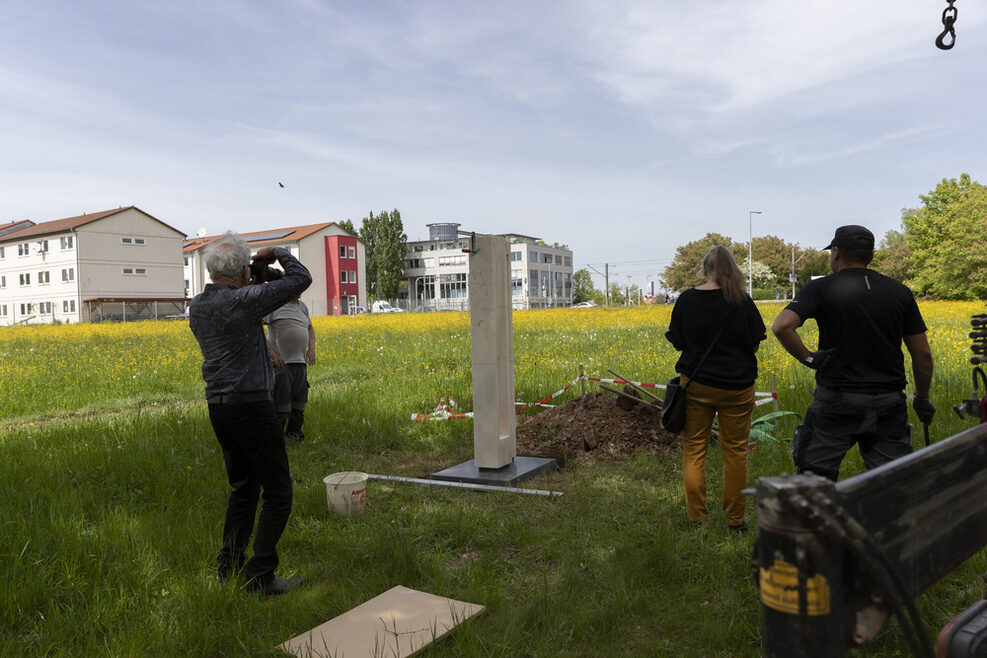 Weiße Plastik auf einer Wiese, die gerade wieder aufgestellt wird.