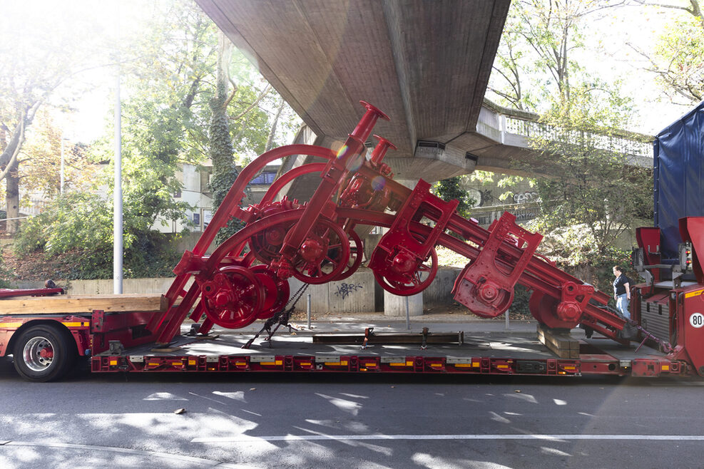 Eine rote Plastik wird von einem Lkw transportiert.