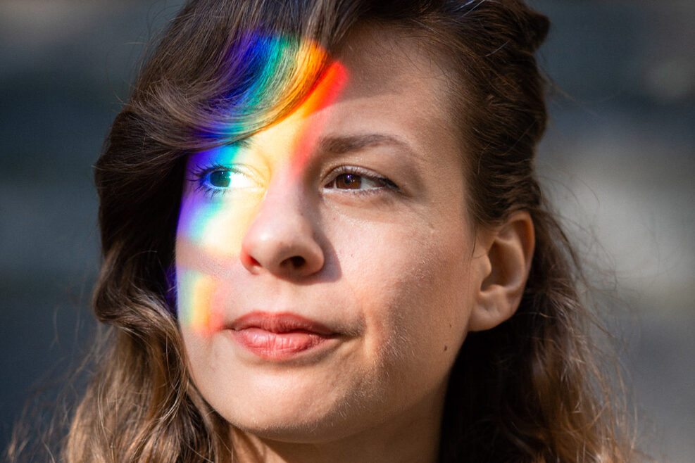 Portraitfoto von Georgia Koumará mit einem Regenbogen Lichteffekt über dem linken Auge.