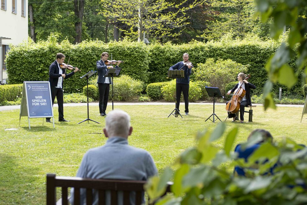 Vier Msuker spielen vor einem Mann ein Konzert.