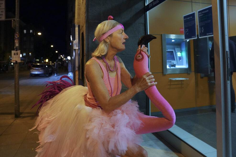 Eine Frau im Flamingo-Kostüm schaut in ein Schaufenster