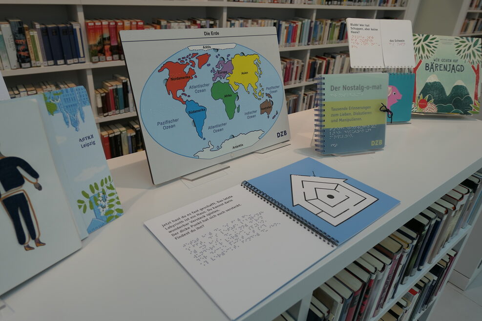 Einn Tisch mit Inklusisionsmaterialien: u.a. Bücher und ein Atlas zum Fühlen