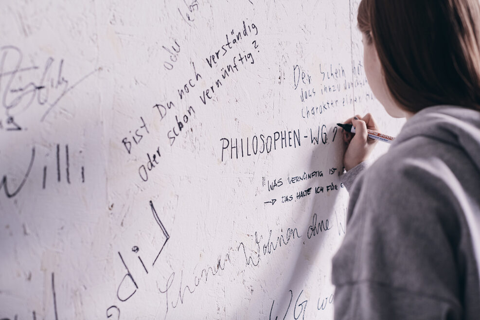 Eine Frau schreibt an eine Wand in der WG des Hegel-Hauses