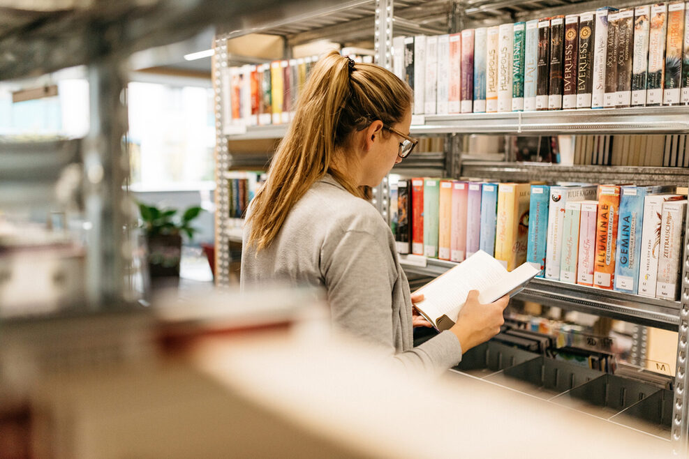 Eine Bibliotheksnutzerin am Bücherregal