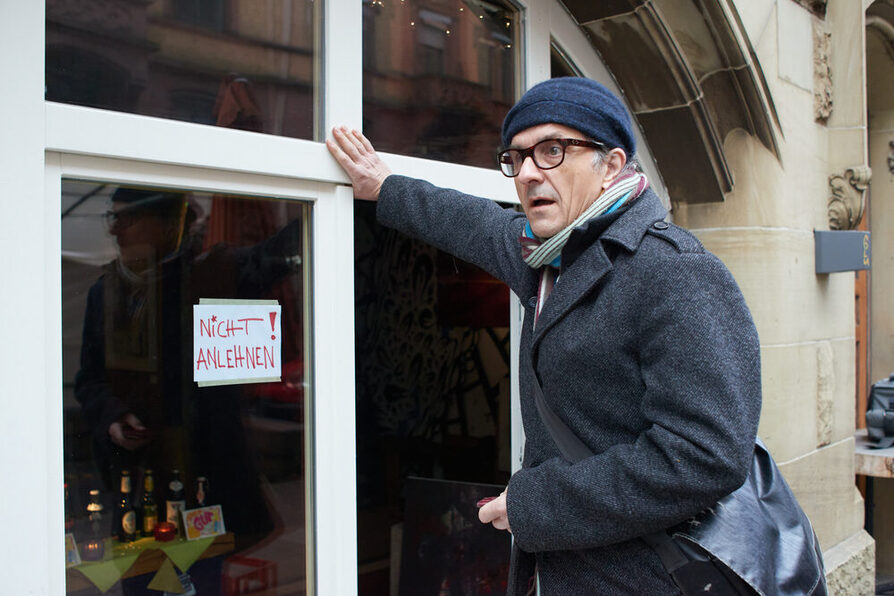 Ein Mann lehnt an einem Fenster mit der Aufschrift "Nicht anlehnen."