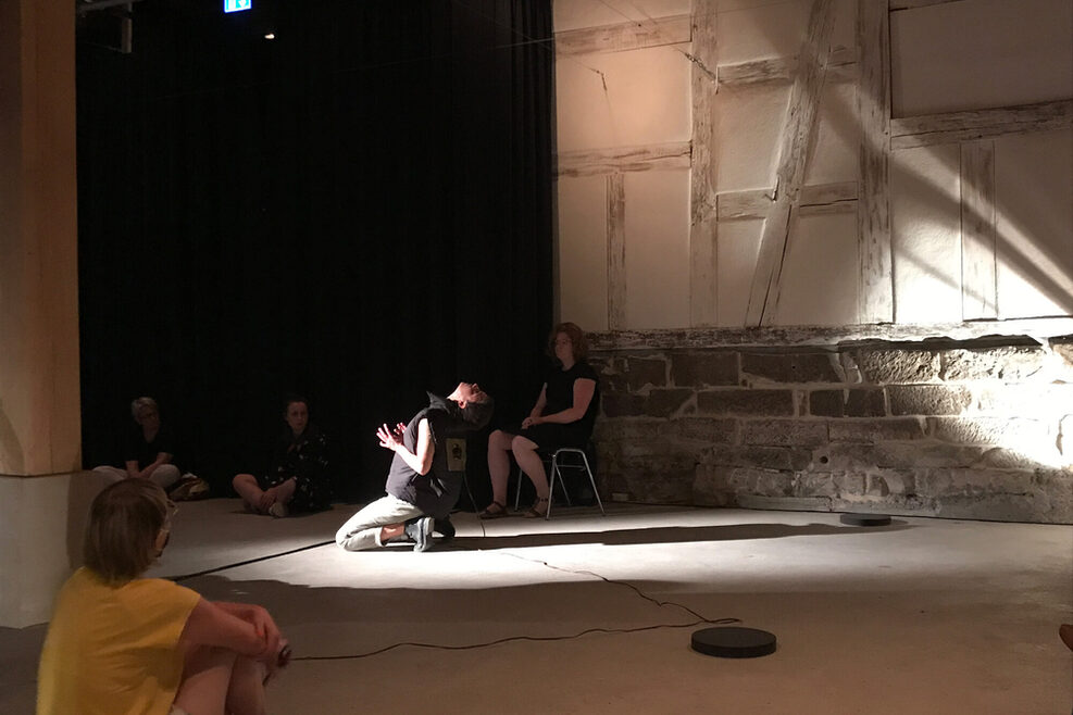 Menschen schauen einem Tänzer bei seiner Show in einem rustikalen Saal zu.