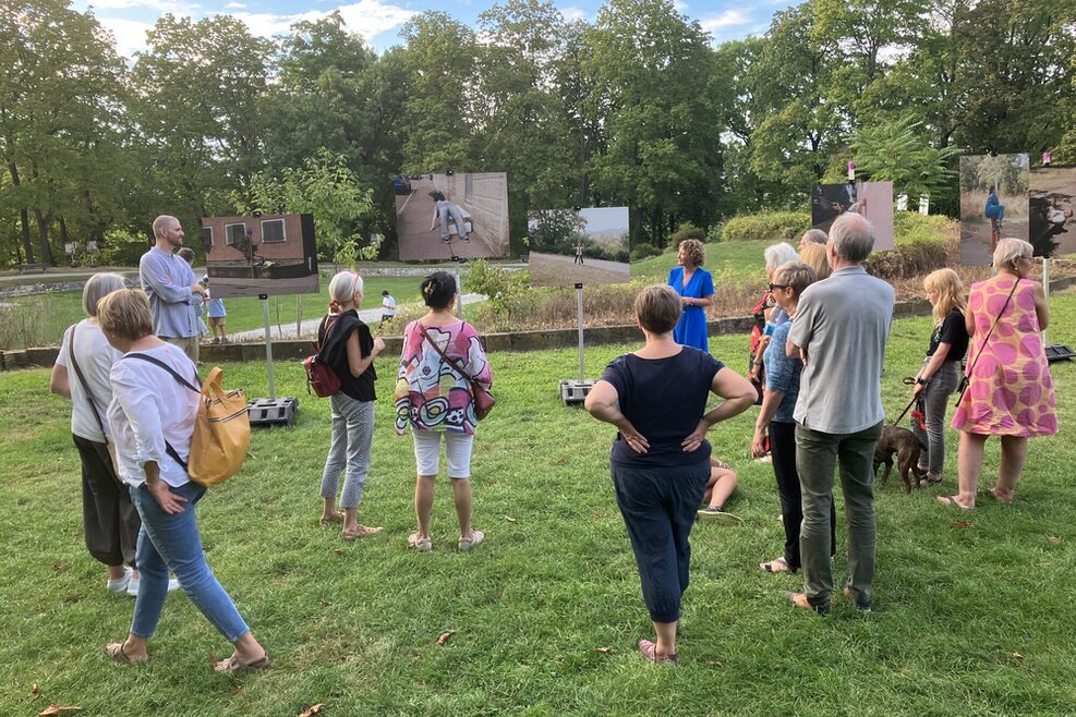 Mitglieder des Planungsstabs Villa Berg führen Besucherinnen und Besucher durch die Fotoausstellung "Exploring the City" im Park der Villa Berg.