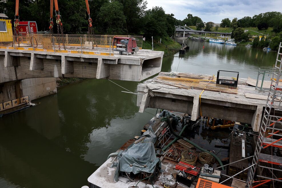 Die verbliebenen Brückenträger der Rosensteinbrücke werden entfernt. Im linken Bereich ist zu erkennen, wie ein Beton-Brücketräger mithilfe eines Krans angehoben wird.