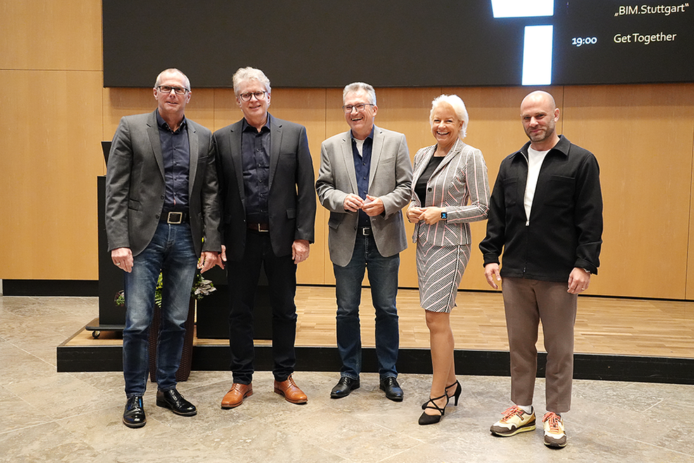 Bürgermeister Thürnau und die Referenten des Abends, Herr Beck, Herr Mohl, Frau Klemt-Albert und Herr El Jundi, stehen für ein Gruppenfoto vor der Anzeigetafel des großen Sitzungssaals des Stuttgarter Rathauses.