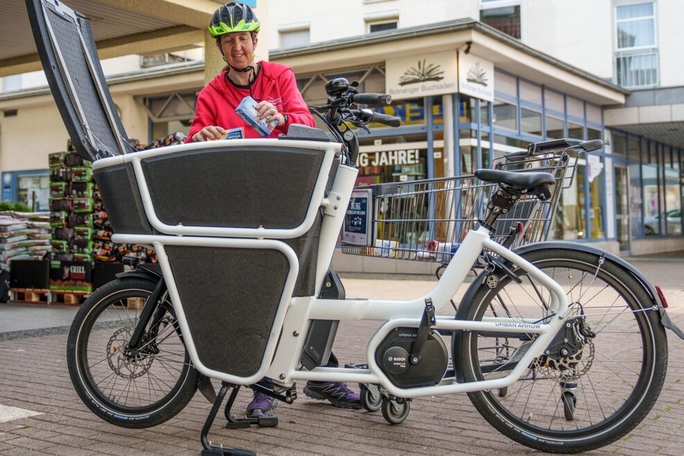 Eine Mitarbeiterin eines Pflegedienstes belädt ein Lastenrad.