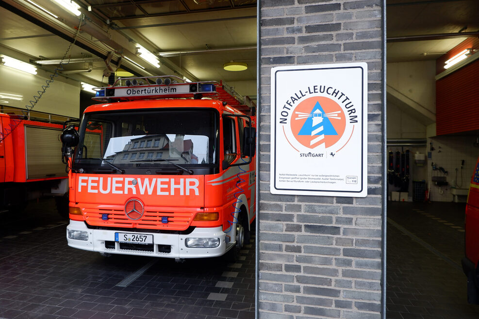 Schild mit der Aufschrift "Notfall-Leuchtturm", ein Kreis in Orange und Leuchtturm-Grafik