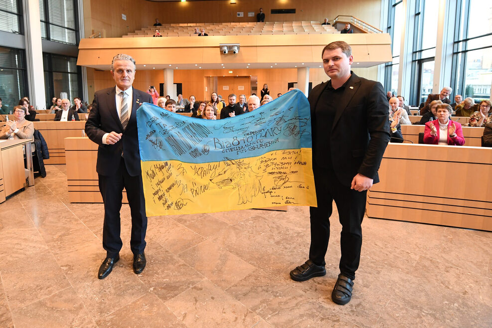 Stuttgarts Oberbürgermeister Dr. Frank Nopper und Bürgermeister Mykola Wawryschtschuk aus Chmelnyzkyj halten im Gemeinderat eine signierte ukrainische Flagge.