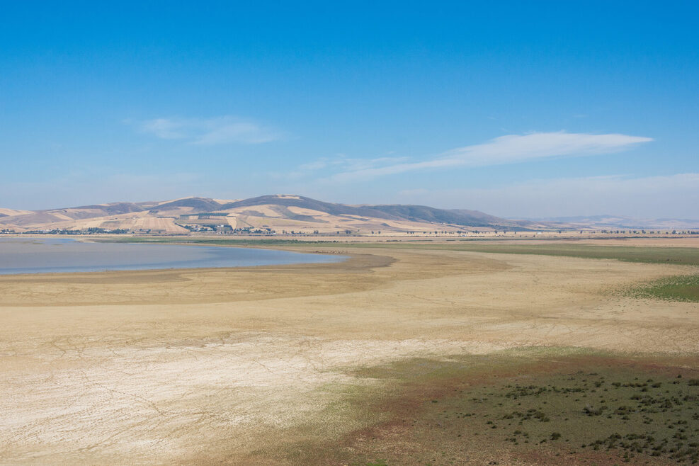 Blick auf eine wüstenähnliche Landschaft mit einem See und einem Berg am Horizont