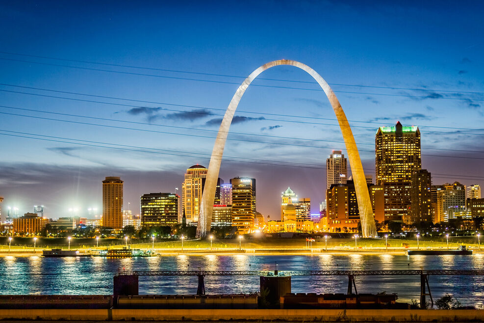 Nachtaufnahme der Skyline von St. Louis mit den Mississippi im Vordergrund.