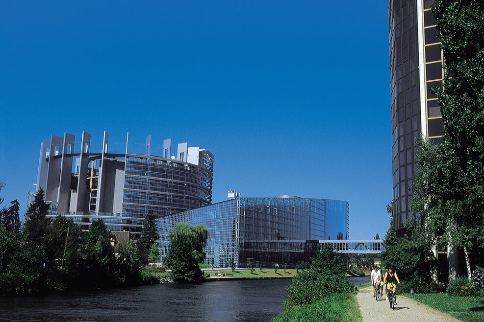 Zwei moderne Glasgebäude stehen am Ufer eines Flusses.