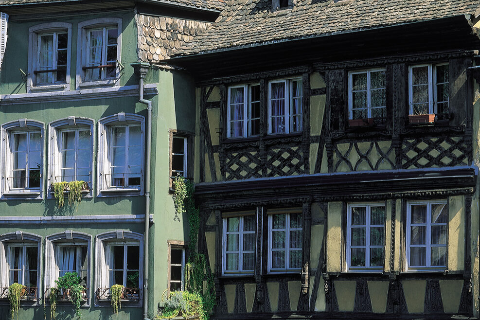 Zwei historische Häuser: eines grün angestrichen, das andere gelb mit Fachwerk.