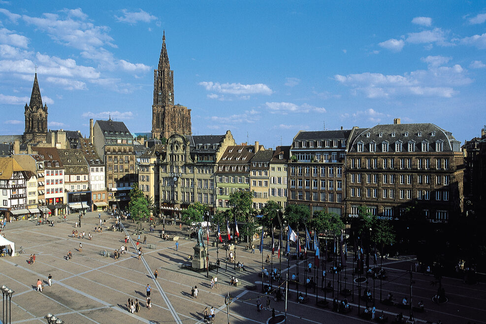 Ein großer, belebter Platz in der Stadt, im Hintergrund ist das Münster zu sehen.