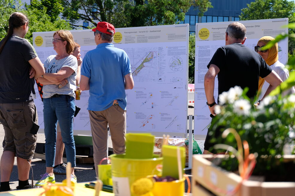 Menschen stehen vor großen Plakaten auf denen Stadtplände des Areals zu sehen sind