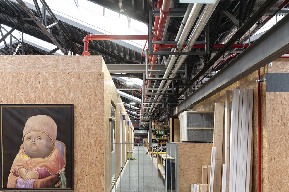 Einblick in die Wagenhallen: links zeigt ein gemaltes Bild einen dicken Mann und die Aufschrift y tho, rechts lehnen Bretter an der Wand, rote und weiße Rohre an der Decke