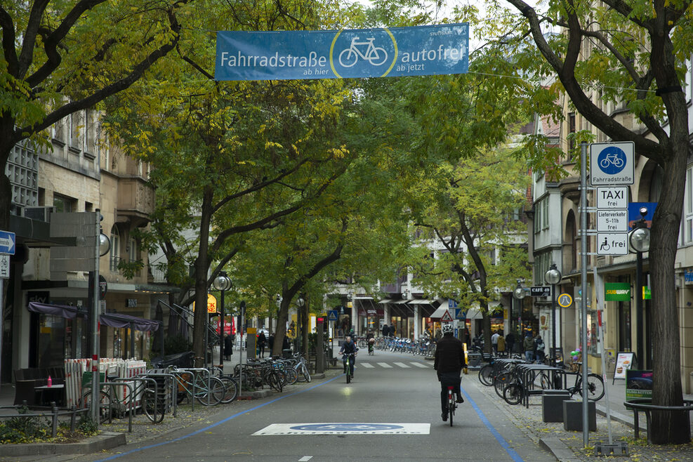 Blick in die Eberhardstraße, die nun eine Fahrradstraße ist. Markierungen sind auf dem Boden angebracht, Radfahrer fahren durch die Straße.