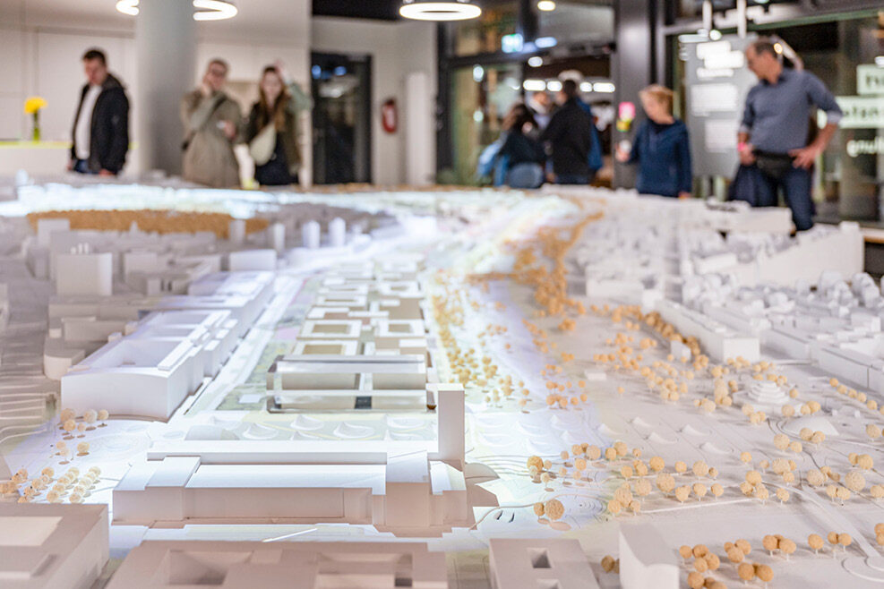 In der Mitte des Bildes steht das Stadtmodell, das von Menschen betrachtet wird