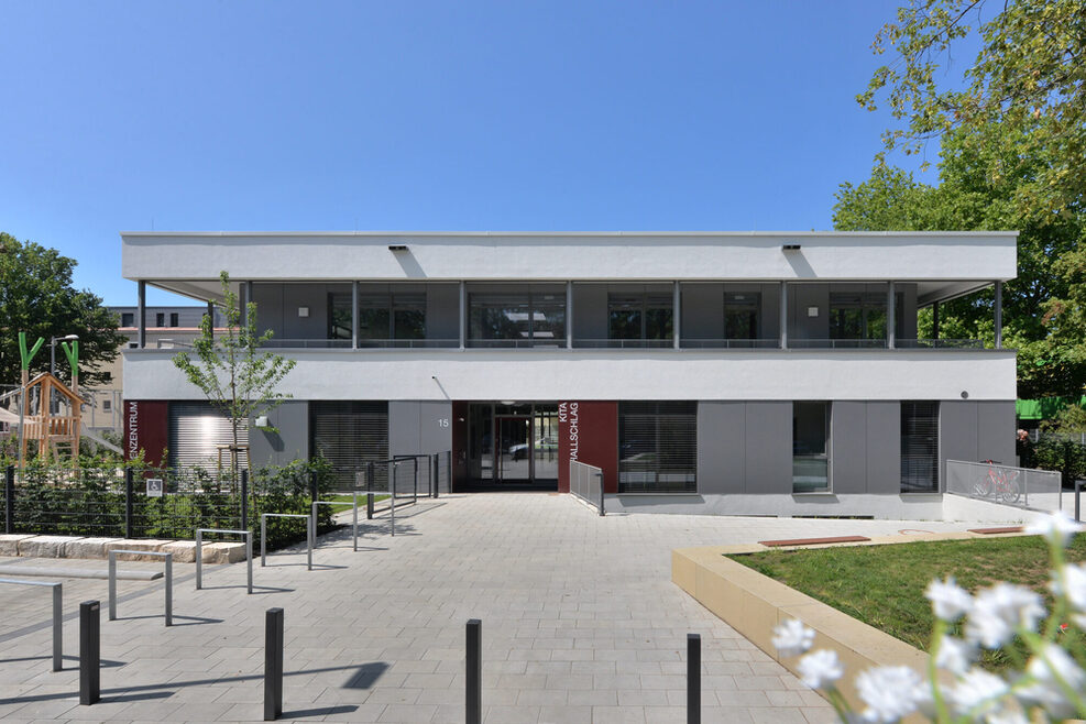 Vor dem Gebäude der Kita Rostocker Straße in Bad Cannstatt befindet sich ein Vorplatz mit Fahrradständern, Sitzmöglichkeiten und Einblicken in den Außenbereich des Kindergartens.