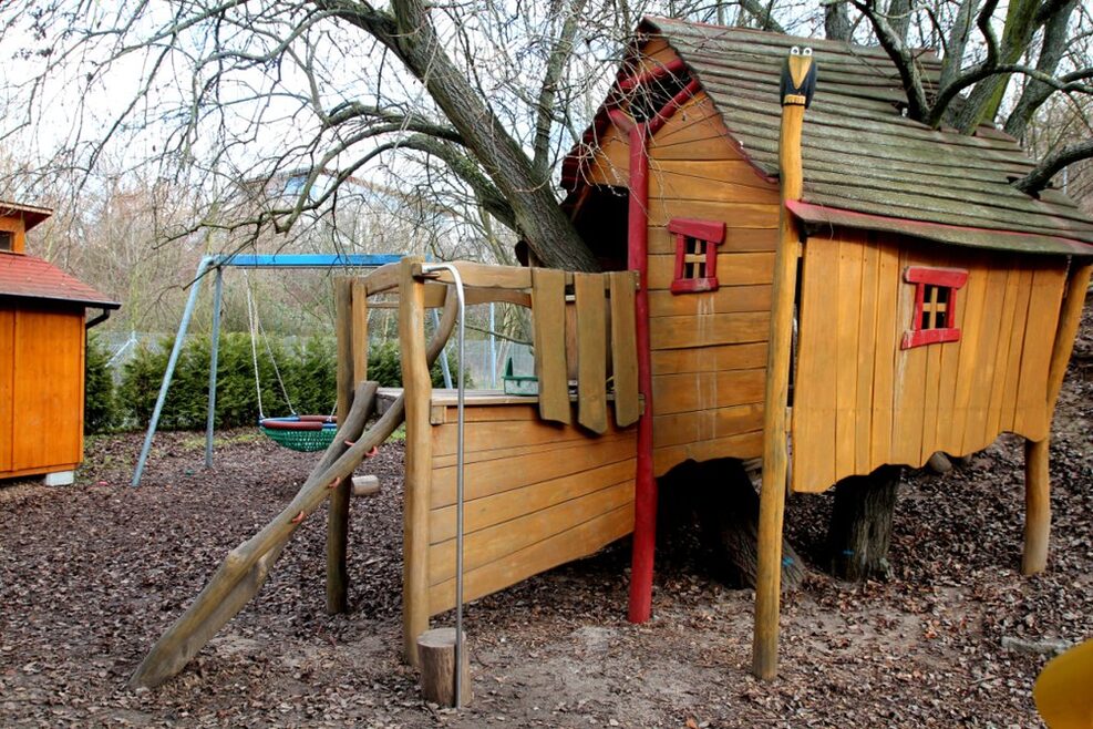 Auf dem Spielplatz können die Kinder im Kletterhäuschen klettern und schaukeln.