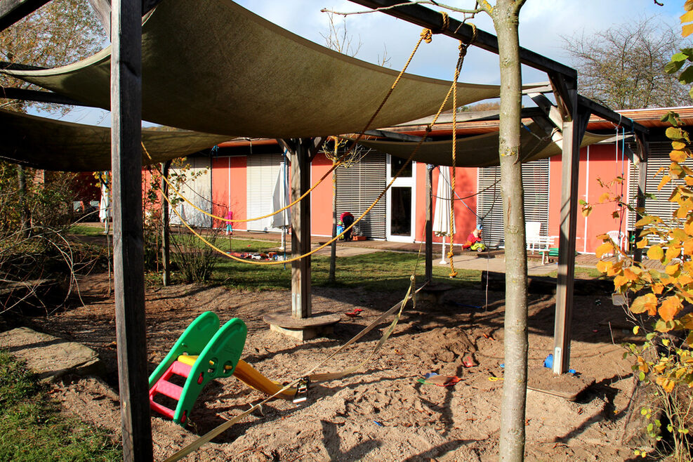 Unser Außenbereich mit Sandkasten und Rutsche.