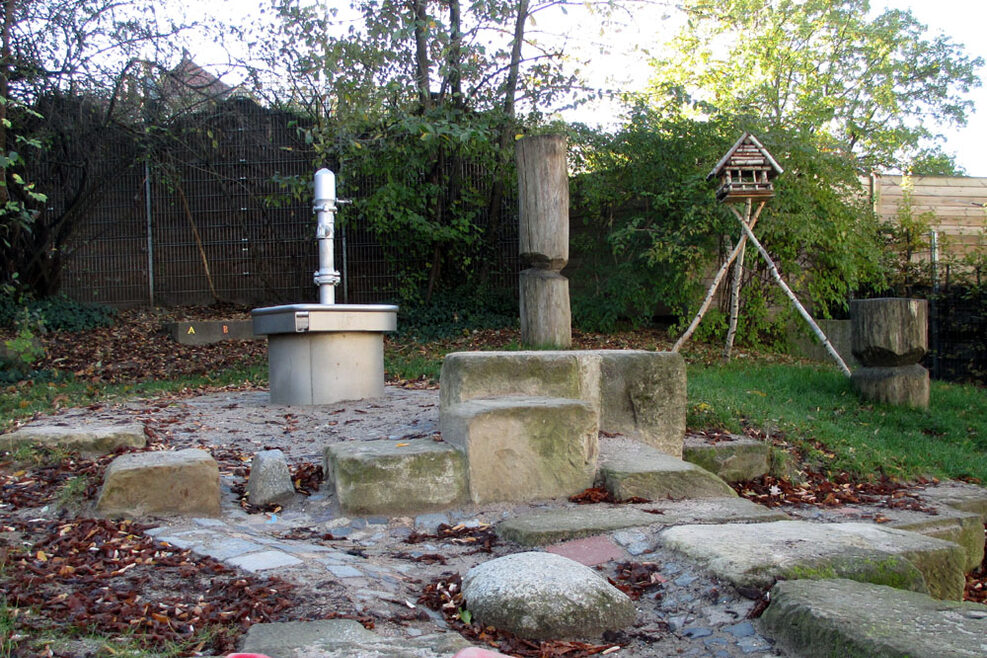 Wasserpumpe und Klettergarten im Außenbereich.