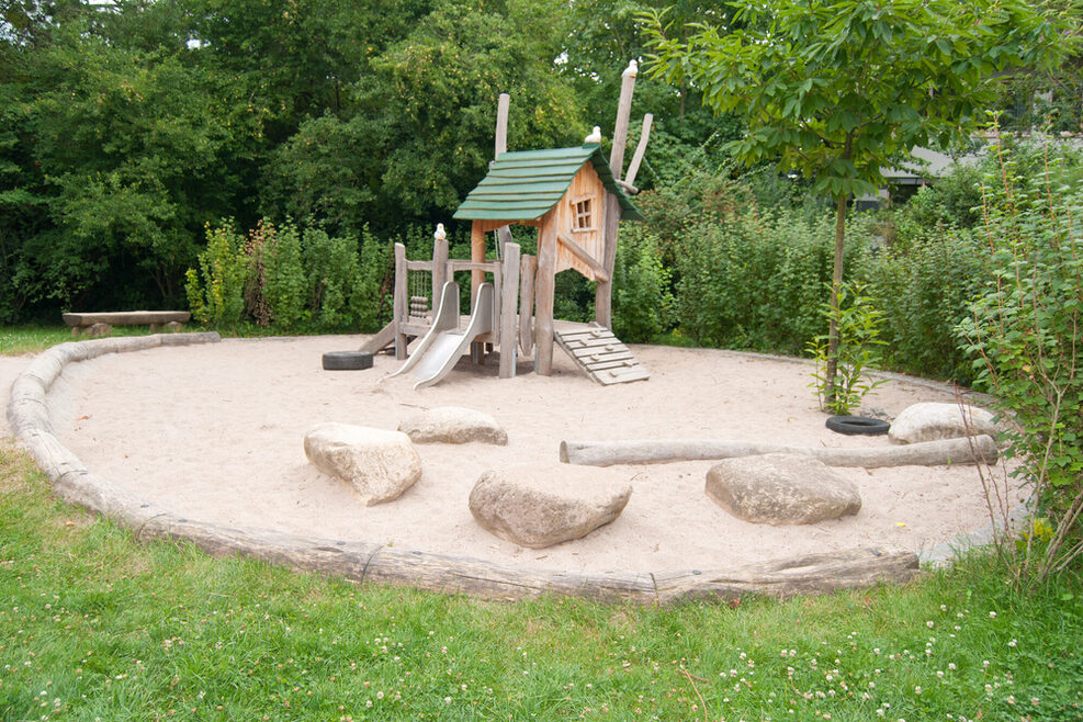 Im Gartenbereich gibt es für die Kleinen einen Abenteuerspielplatz mit Klettergerüst und Sandkasten.