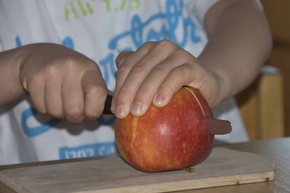 Kinder lernen ganz alltägliche Sachen wie Äpfel schneiden.
