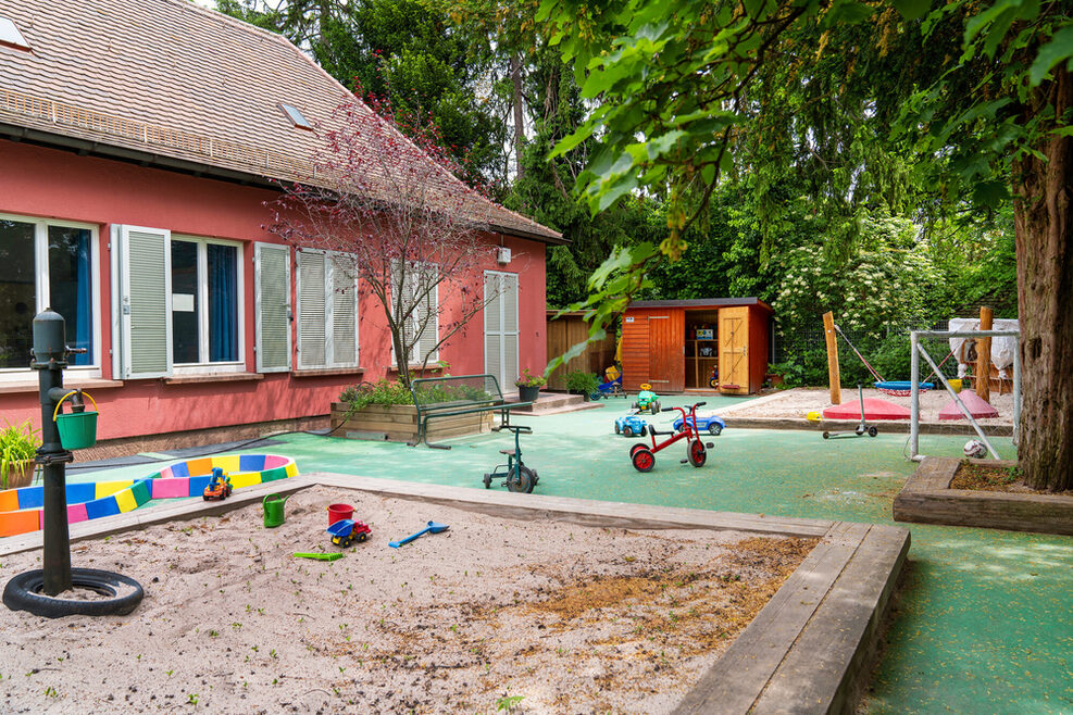 Auf dem Spielgelände können die Kinder im Sandkasten spielen, Dreirad fahren oder Fussball spielen.