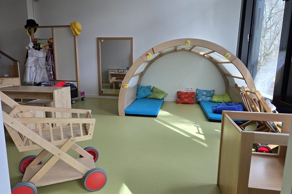 Pictured is a room with a cuddly cave, a wooden shopping cart and dressing-up materials.