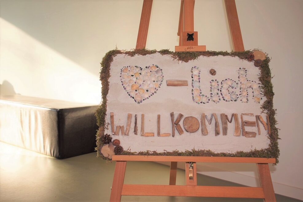 Gestaltetes Begrüßungschild mit Aufschrift Herzlich Willkommen.