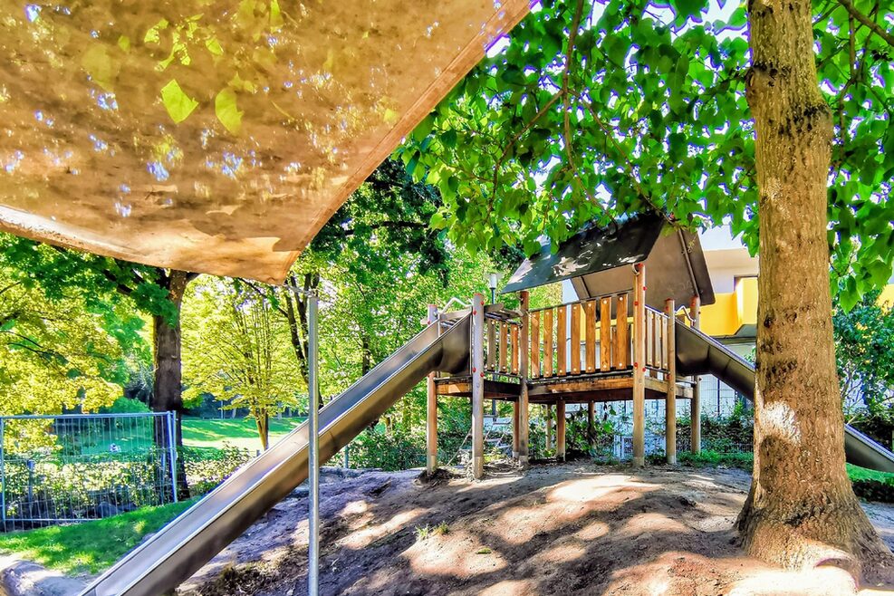 Ein großer Abenteuerspielplatz mit zwei Rutschen wartet auf die Kinder.