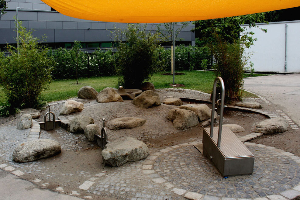 Im Steingarten mit Wasserstraßen können die Kinder ihrer Phantasie freien Lauf lassen, bauen und matschen.