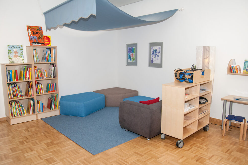 Ein Raum mit Kuschelecke und Büchern lädt zum gemütlichen Vorlesen ein.