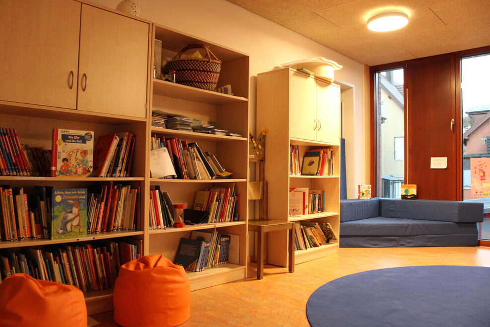 Gefüllte Bücherregale für Kindergartenkinder mit Sitzmöglichkeiten.
