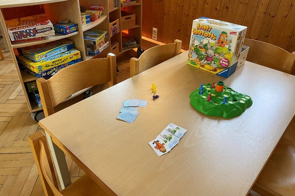 Tisch und Stühle für Kinder mit Regal voller Gesellschaftsspiele.
