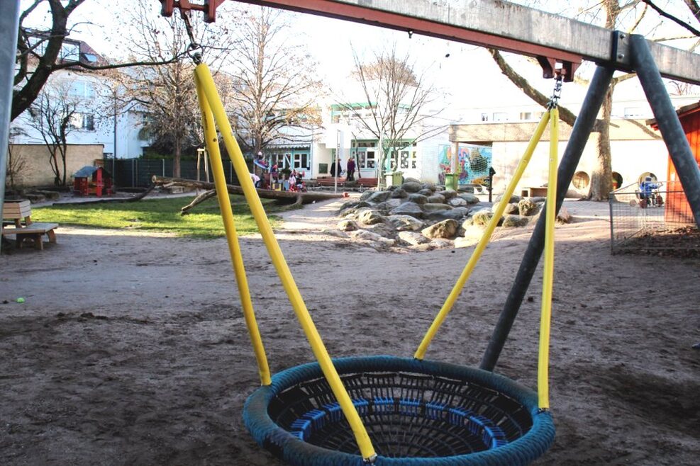 Der Spielplatz mit Korbschaukel und uns Steinklettergarten.