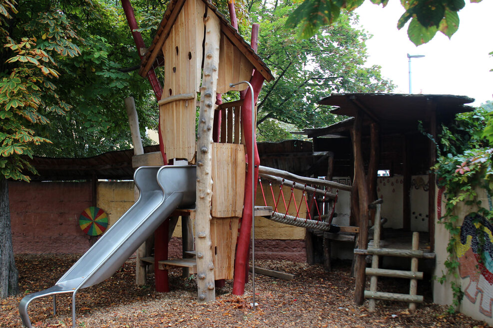 Im Außenbereich wartet ein Abenteuerspielhaus mit Rutsche auf die Kinder.