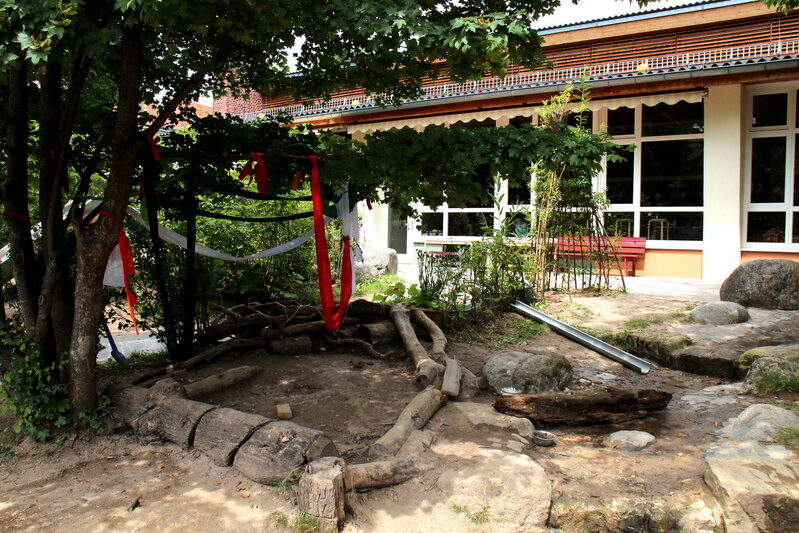 Außenbereich mit Steinen, Holzbalken und Wasserrinne.