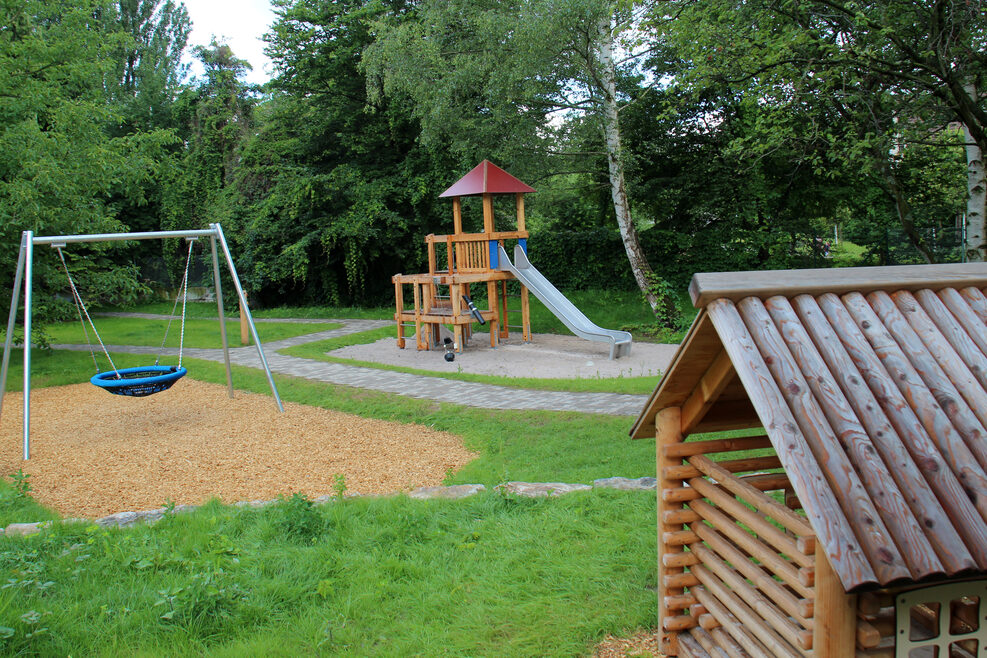 Der große Spielplatz mit Klettergerüst, großer Rutsche und Korbschaukel.