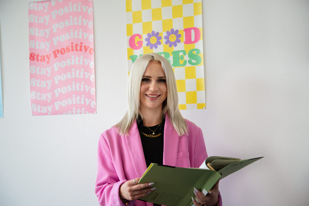 Junge Frau mit pinkem Blazer lacht freundlich in die Kamera