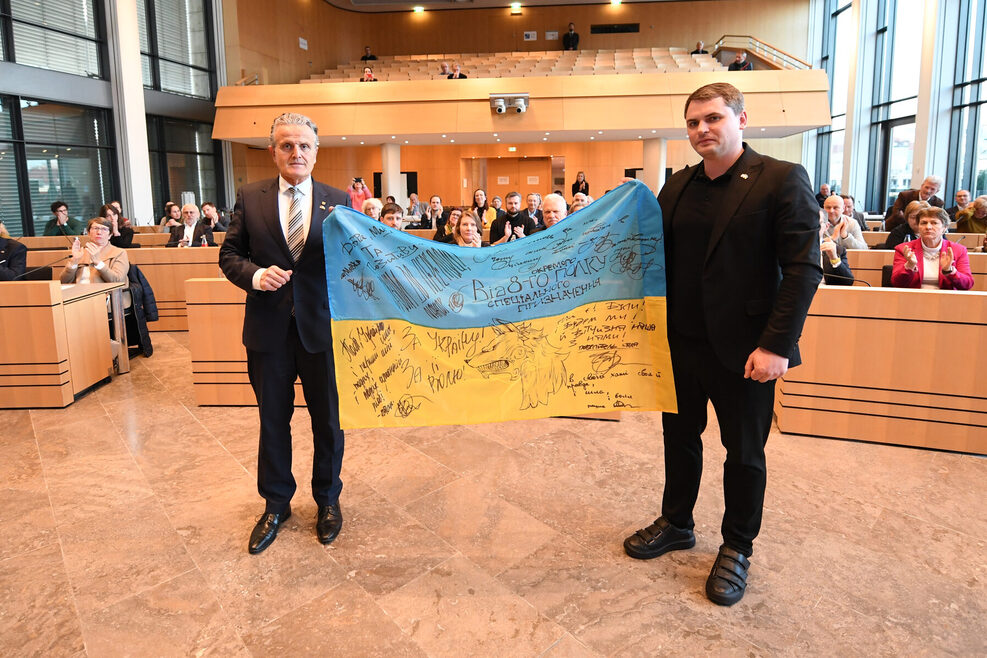 Stuttgarts Oberbürgermeister Dr. Frank Nopper (links) und Bürgermeister Mykola Vavryshchuk aus Chmelnyzkyj halten im Gemeinderat eine signierte ukrainische Flagge.