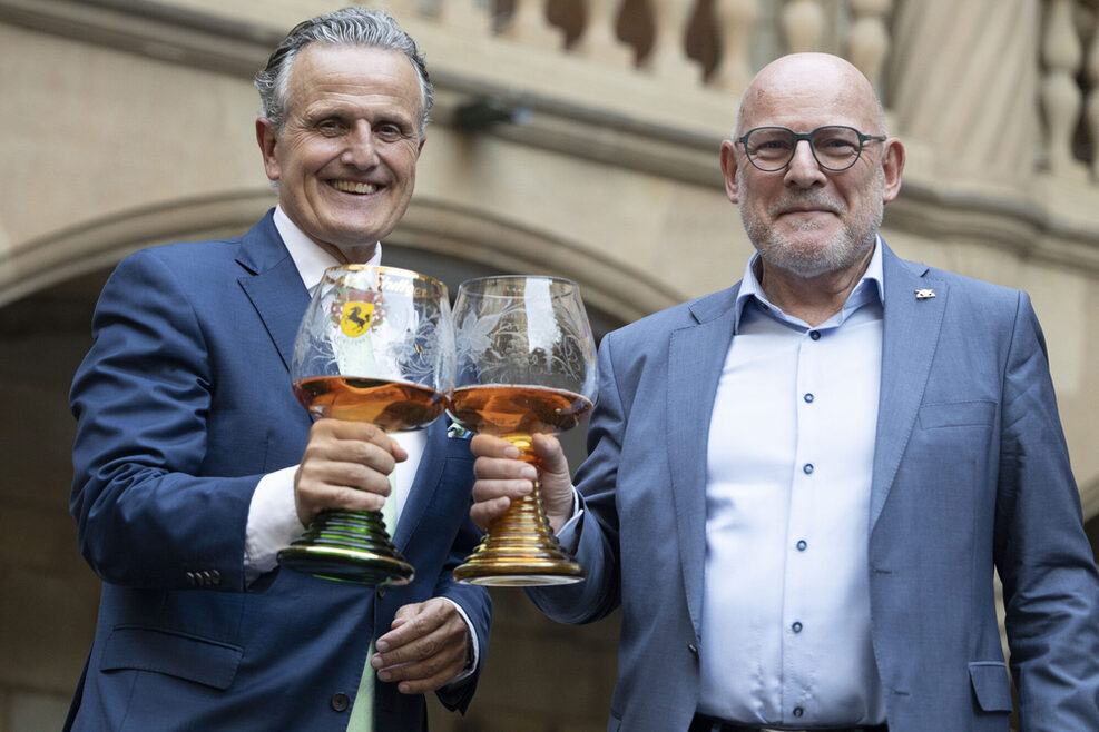 OB Nopper und Verkehrsminister Winfried Hermann stoßen mit zwei großen Kelchen Wein an.